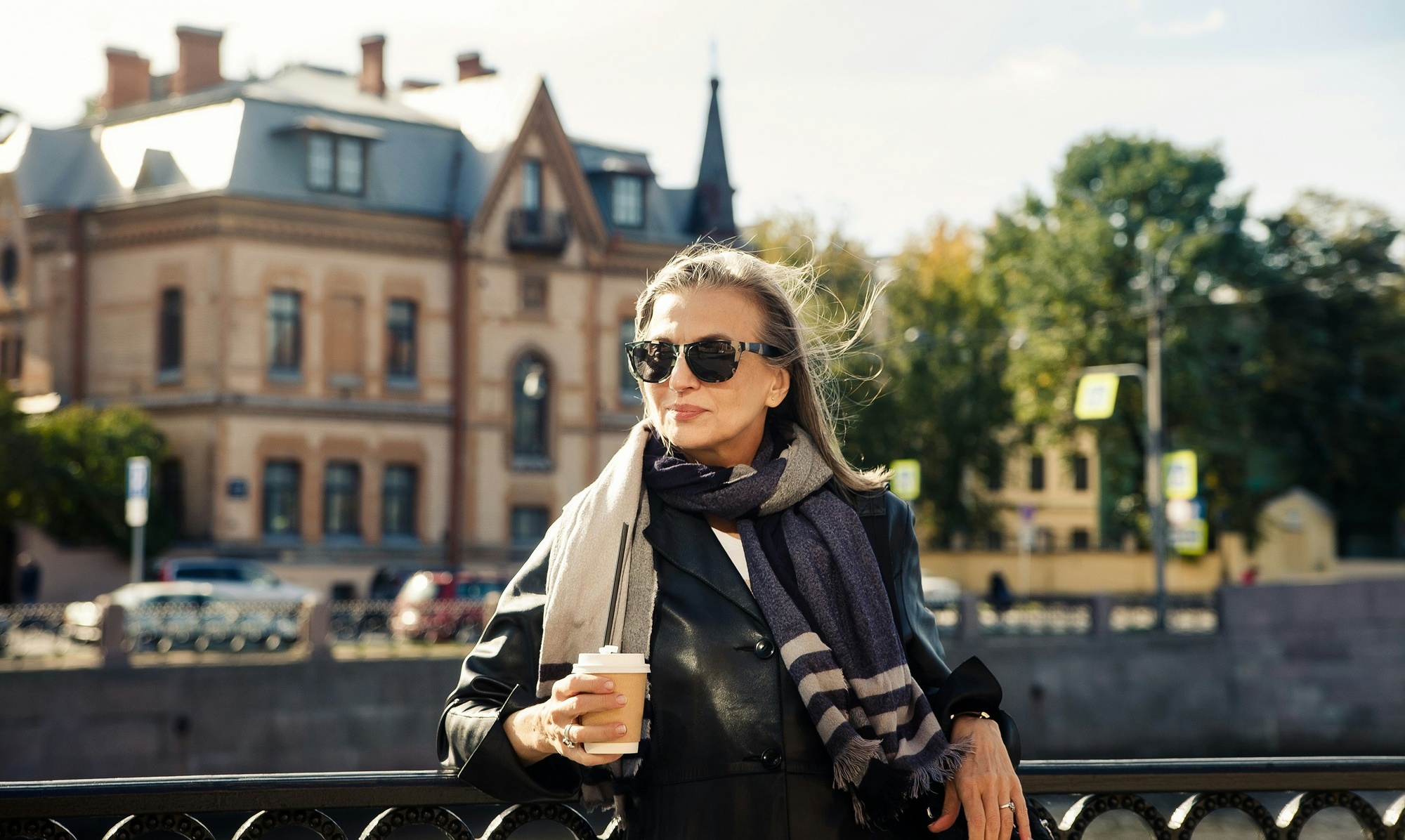 Stylish older woman holding coffee cup outdoors in the city